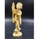 A JAPANESE IVORY FIGURE OF A LADY HOLDING UP A BUNCH OF GRAPES, SIGNED. H.14CMS.