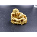 A JAPANESE MARINE IVORY NETSUKE CARVED AS A DAIKOKU TACKLING AN ONI ATTEMPTING TO RAID HIS SACK OF