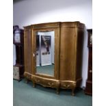 A LARGE CONTINENTAL GILT ARMOIRE IN THE ROCOCO TASTE WITH CENTRAL MIRROR DOOR AND THREE DRAWERS TO