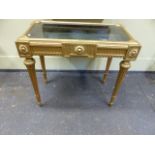 A CARVED GILTWOOD FRENCH LOUIS XVI.STYLE BIJOUTERIE TABLE WITH GLAZED LIFT TOP AND TAPERED FLUTED