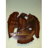 A 19TH/20TH.C. CONTINENTAL CARVED WALNUT SPREAD WING EAGLE HOLDING A BEVELLED CRESCENT FORM MIRROR