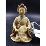 A JAPANESE IVORY FIGURE OF A LADY KNEELING HOLDING A FAN, HER KIMONO ENGRAVED WITH FLOWERS AND