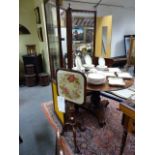 A VICTORIAN CARVED ROSEWOOD POLE SCREEN WITH NEEDLEWORK FLORAL PANEL ON SCROLLING TRIFID LEGS.