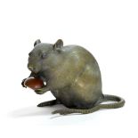 A vividly detailed bronze rat standing on its hind legs with paws holding a copper chestnut. The