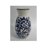 19th century blue and white painted Delft style vase with decorative scrolling foliage on a white
