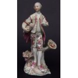 Derby figure of a man with fruit on a scroll base in typical colours, circa 1765, some losses, 20cms