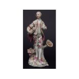 Derby figure of a man with fruit on a scroll base in typical colours, circa 1765, some losses, 20cms