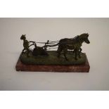 Bronze group of two horses drawing a plough with a young man to back, raised on a red marble plinth,