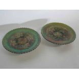 Pair of carnival glass plates raised on three feet, with a grape and vine design, each 23cms diam
