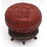 A large Chinese circular cinnabar lacquer box and cover with carved hardwood stand, the lid