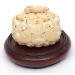 Japanese ivory box (base missing), carved as a multitude of faces, associated wood stand, Meiji