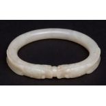 Chinese jade bangle of very pale celadon or white colour carved with confronting dragon heads with a