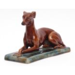 Mintons, England, majolica glazed model of a reclined greyhound on a mottled green base, 17cms