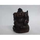 Chinese hardwood carved seated figure with a fish under his arm, with painted character marks to