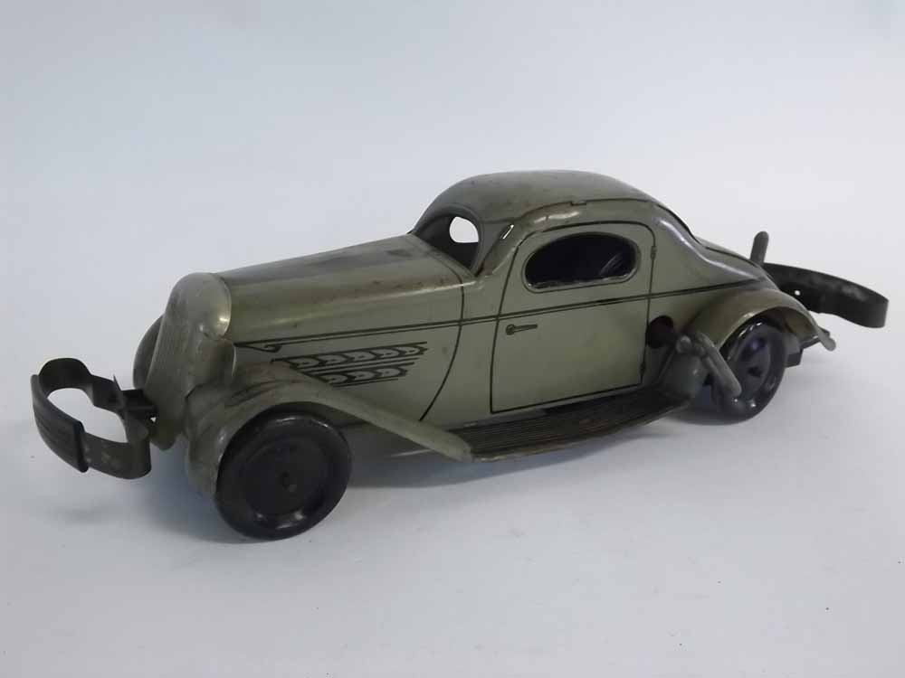 Vintage tin plate clockwork double bump and go saloon car, painted in green with black outlines,