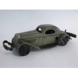 Vintage tin plate clockwork double bump and go saloon car, painted in green with black outlines,