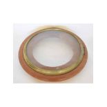 Concave cast brass bezel set with convex glass together with a plain unfinished turned mahogany