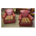 Pair of red leather upholstered club chairs with striped upholstered cushions, raised on bun feet