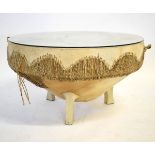 Large hide covered circular drum formed table with a three-footed base and a glass top, 90cms diam x