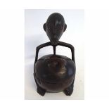 Specific ceremonial Kava bowl and lid with a carved figure holding it, baring his teeth, 19cms tall