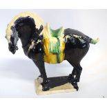Black glazed standing Tang style horse with green and yellow detail to saddle, 25cms tall