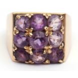 Yellow metal and amethyst cluster ring, a square panel claw set with 9 circular faceted amethysts in