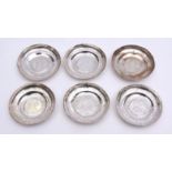 Six Middle Eastern white metal circular dishes with engraved rims and coin inset centres, diameter