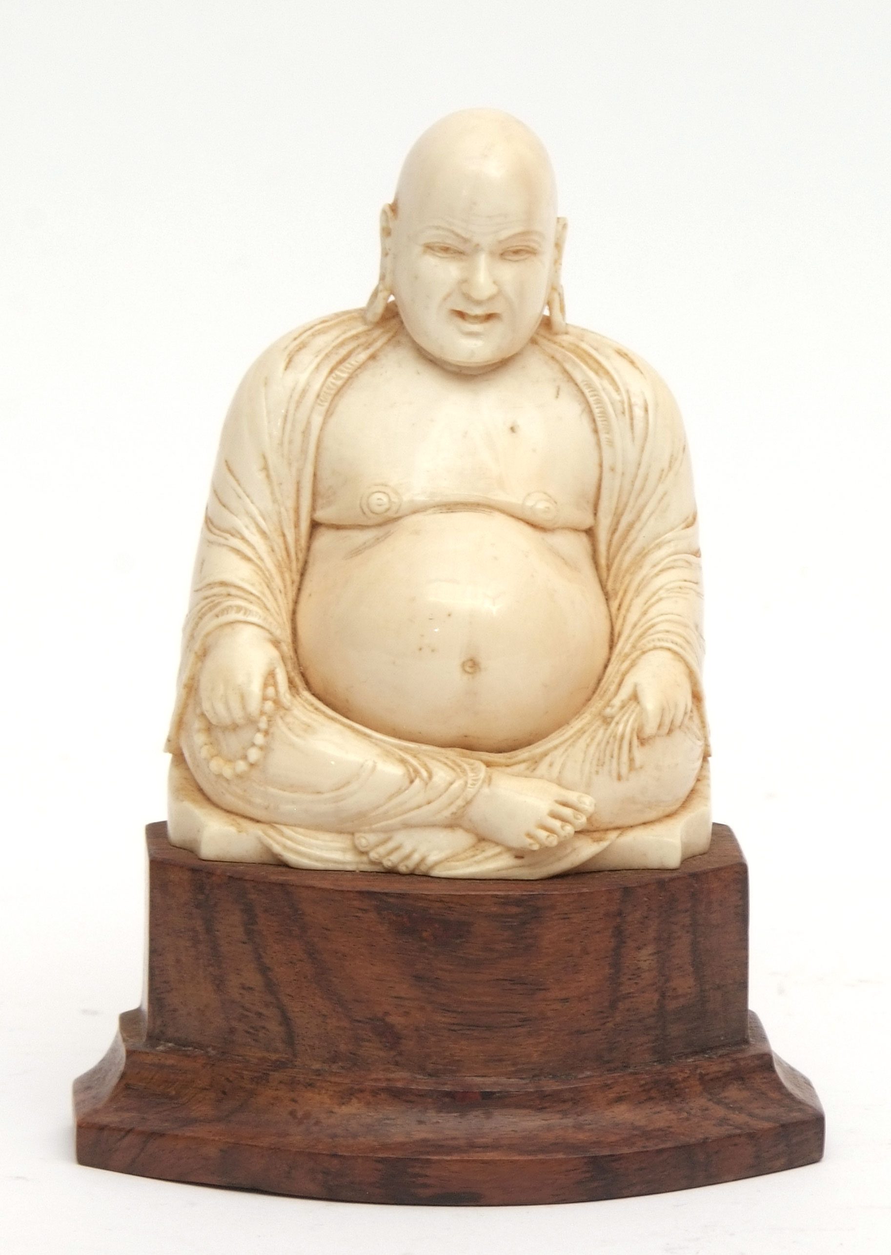 Oriental, possibly Chinese, ivory carving of Budai seated cross-legged, holding a string of beads,