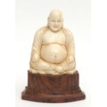 Oriental, possibly Chinese, ivory carving of Budai seated cross-legged, holding a string of beads,