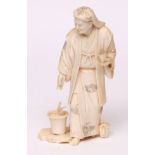 Early 20th century carved ivory figure in the form of a gardener, wearing a head-dress and with