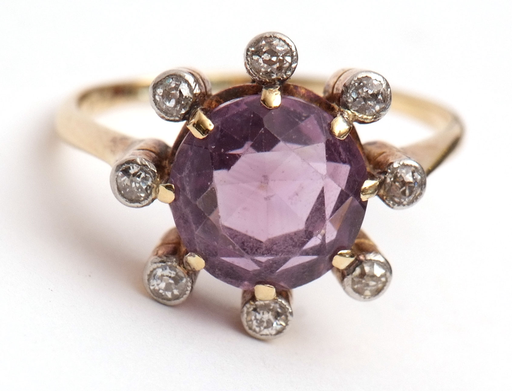 Precious metal amethyst and diamond ring, the circular-shaped amethyst is within a surround of 8