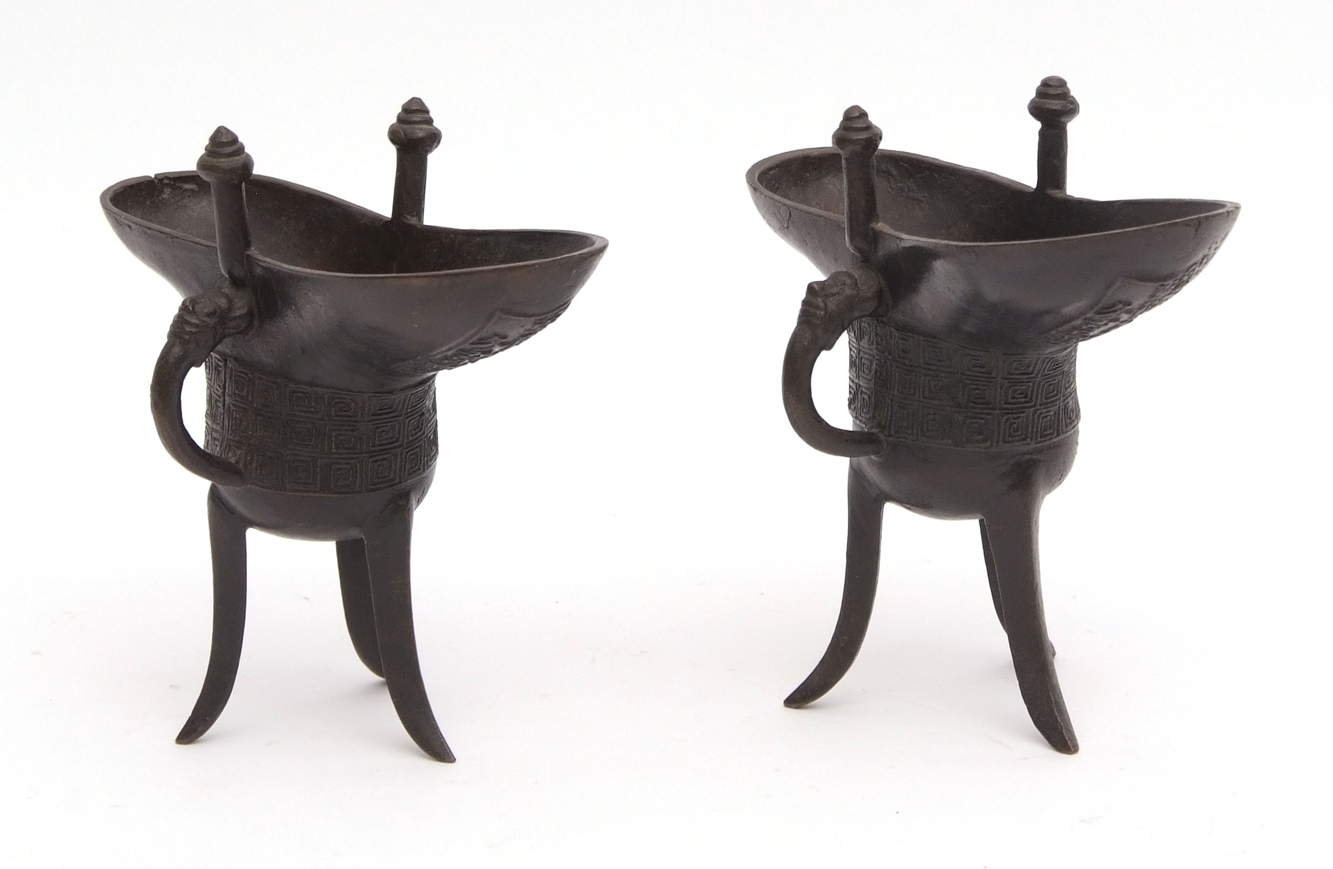 Two Chinese bronze ritual vessels of tripod form in archaic style, with cast geometric design, 8