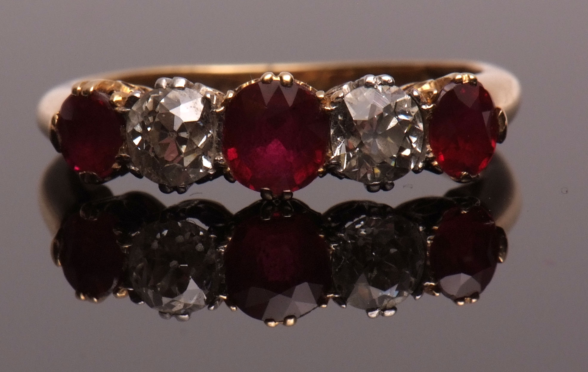 Diamond and ruby five-stone ring, alternate set with three graduated circular cut rubies and two