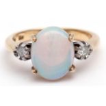 Precious metal opal and diamond ring, the central opal (12 x 8mm) set between two small circular cut