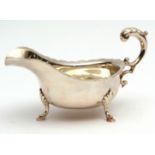 George V gravy boat of typical form with cut card rim, leaf capped flying C-scroll handle and raised