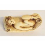 Japanese ivory netsuke modelled as a recumbent nude of a lady on a scroll, signed to reverse