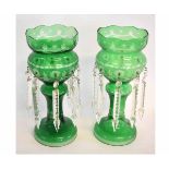 Pair of green cut glass lustres, each with prismatic drops and raised on circular bases, 37cms tall