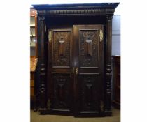 French oak armoire with two doors with heavily carved panels with stepped centres and Corinthian