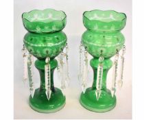 Pair of green cut glass lustres, each with prismatic drops and raised on circular bases, 37cms tall