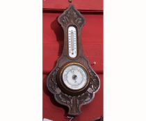 Early 20th century carved oak aneroid barometer, the case with floral and foliate detail, set with a