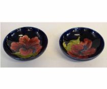 Pair of Moorcroft circular pedestal small bowls, Hibiscus pattern to a blue ground, 14cms diam,