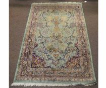 Modern Indian type floor rug with a green ground and central urn and floral border, 93cms wide x