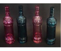 Four decorative French coloured bottles or decanters, in pink and green, with moulded decoration,