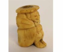 Oriental carved bone netsuke of a seated figure (drilled), 4cms tall