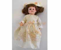 Small German porcelain headed doll with waxed limbs, dressed, 25cms tall