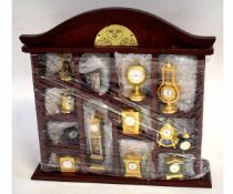 Teak case containing 13 assorted miniature quartz clocks to include a mantel clock, alarm clock,