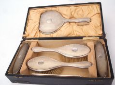 George V cased dressing table set comprising hand mirror, pair of hair brushes, pair of clothes