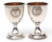 Two George V egg cups, each with plain polished bowls and gilt lined interiors and with applied