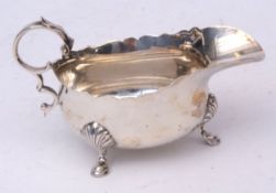 George V sauce boat with cut card rim, leaf capped handle and applied feet, length 12 1/2 cms,