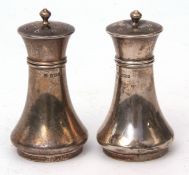 Two George V pepper casters, each of waisted form with pierced pull off covers, height 8cms,